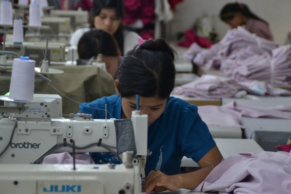 Überstunden, Überwachung und Gewalt 40 Eine Frau sitzt an einer Nähmaschine. Im Hintergrund sind weitere Reihen von Näherinnen zu sehen.