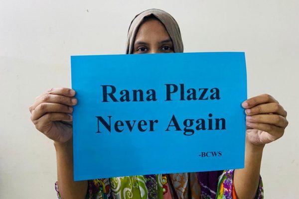 Rana Plaza: Der Accord muss weitergehen 7 Eine Frau hält ein blaues Schild hoch. Darauf steht: "Rana Plaza Never Again"