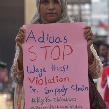 adidas-Hauptversammlung 2025: Hungerlöhne und Abfindungsdiebstahl 3 Eine Frau hält ein rosafarbenes Plakat hoch. Daruaf steht unter anderem: "Adidas, Stop Wage theft"