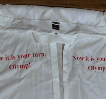 Auf ein weißes Hemd ist links und rechts ein roter Satz gedruckt.