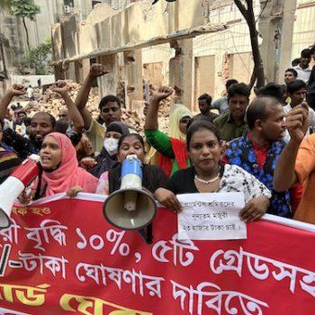 Lohn zum Leben Kampagne für Saubere Kleidung Eine Gruppe Menschen demonstriert mit Megaphonen und einem großen, roten Banner.