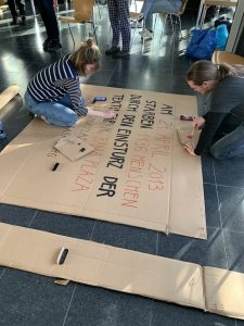 Aktiv werden! 2 Eine Frau und ein Mann knien am Boden und malen auf einen großen Karton.