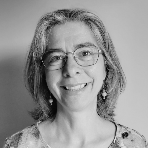 Eine Frau mit Brille blickt lächelnd in die Kamera.