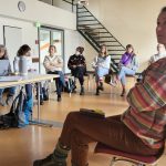 Menschen sitzen auf Stühlen im Kreis