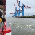 Menschen auf einem Ausflugsschiff, im Hintergrund sieht man Kräne