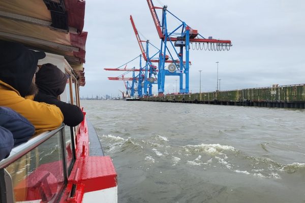 Menschen auf einem Ausflugsschiff, im Hintergrund sieht man Kräne