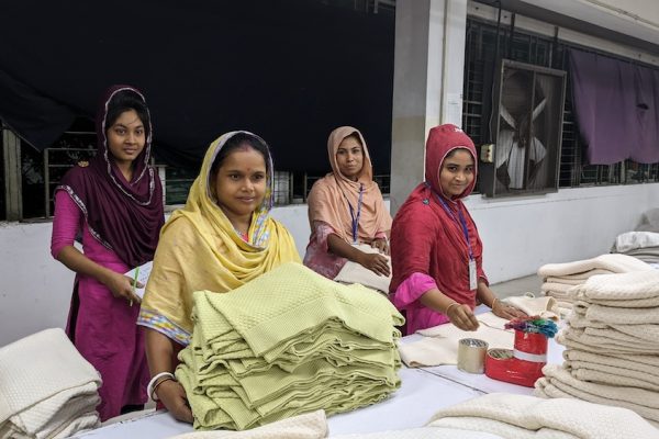 Bangladesch: Speakerstour 11 Jahre nach Rana Plaza 51 Vier bangladeschische Frauen stehen hinter einem Tisch voller Stoffe.
