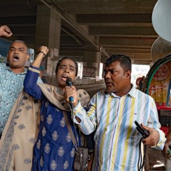 Bangladesch im Umbruch: Die Folgen der Proteste 1 Ein Mann und eine Frau halten mit geöffnetem Mund ihre Faust in die Luft. Ein Dritter hält der Frau ein Mikrofon vor.