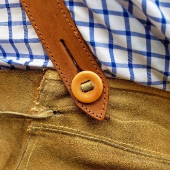 Hintam Berg san aa no Leit – Woher kommt die Lederhose? 3 Hosenbund einer Lederhose, in dem ein blau-weiß kariertes Hemd steckt.