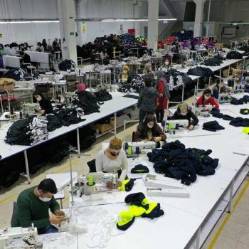 Türkei: Entlassene Textilarbeiter*innen kämpfen erfolgreich für ihre Abfindungen 5 An langen Tischen sitzen Menschen nebeneinander und nähen. Sie tragen Masken.