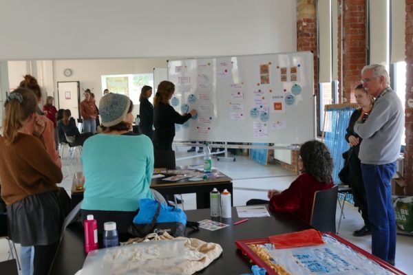 Eine Gruppe Menschen steht vor einem Flipchart