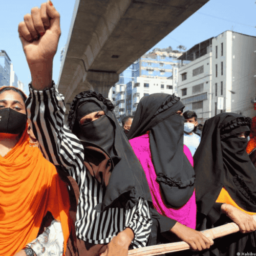 Spenden für die Kampagne für Saubere Kleidung | Clean Clothes Campaign Germany 6 Mehrere Frauen mit Kopftuch und Tuch oder Maske vor dem Mund stehen nebeneinander. Eine reckt ihre Faust in die Luft.